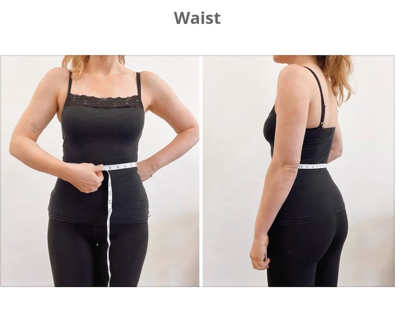 Op de afbeelding: Een persoon in zwarte kleding meet zijn taille met een wit meetlint. Het meetlint geeft 28 inch aan.