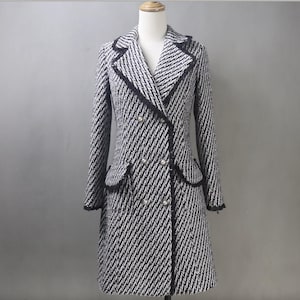 May include: A black and white tweed double-breasted coat with a black trim and pearl buttons.