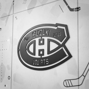 Peut inclure: Logo noir et gris des Canadiens de Montréal avec le texte "SUZUKI" et les années "2025" et "2026". Le logo comprend également le texte "101 PTS". Le logo est sur un fond blanc avec des illustrations de crosses de hockey.