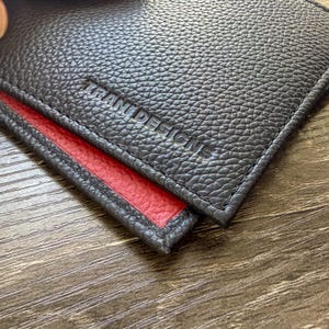 Handgjord tvåfärgad läderplånbok med bifold-mönster – svart utsida, karminröd insida, minimalistisk seddelfold