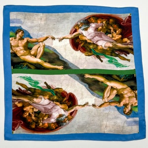 May include: A blue and green framed square scarf with a printed image of Michelangelo's The Creation of Adam. The image is repeated twice, once with the figures on the left and once with the figures on the right.