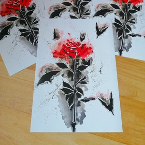 Puede incluir: Cuatro impresiones de acuarela de una rosa roja con murci&eacute;lagos negros volando a su alrededor. La rosa est&aacute; pintada en un estilo realista con una lavada de acuarela.
