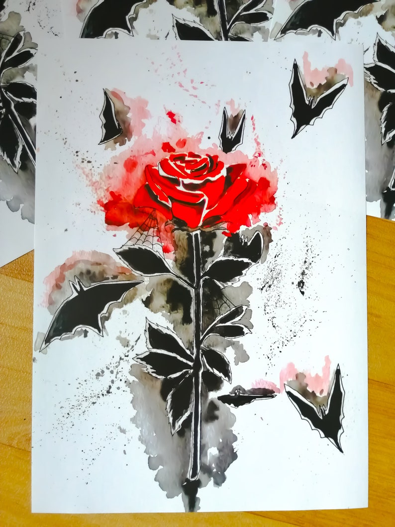 Puede incluir: Una pintura de acuarela de una rosa roja con murci&eacute;lagos negros volando a su alrededor. La rosa est&aacute; rodeada de una lavada de acuarela roja y rosa.