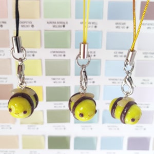 Puede incluir: Tres llaveros con encanto de abeja amarilla y marrón con cordones negro, amarillo y marrón. Los encantos de abeja tienen ojos negros y una boca sonriente.