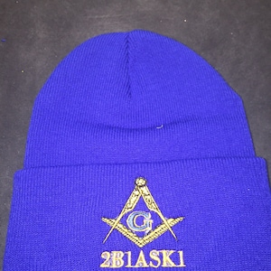 May include: A royal blue knit beanie with a gold embroidered Masonic symbol and the text "2B1ASK1".