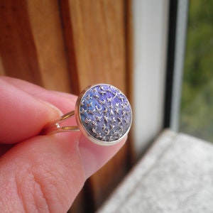 May include: A silver ring with a round blue and purple patterned stone.