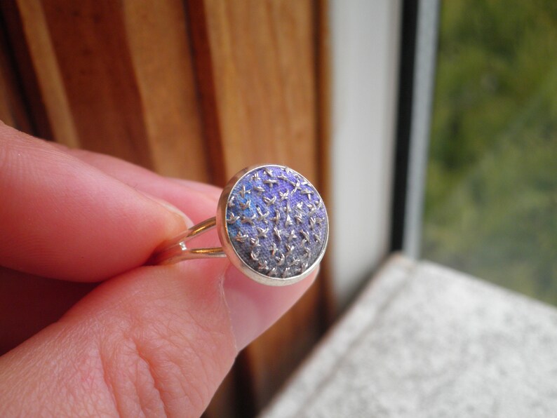May include: A silver ring with a round blue and purple patterned stone.
