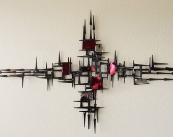 May include: A large, abstract metal wall sculpture with a geometric design. The sculpture is made of black metal and features red accents. It is a modern and stylish piece of art that would add a touch of sophistication to any room.