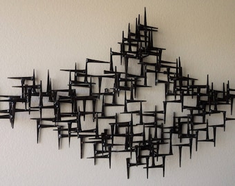 May include: A black metal wall sculpture made of many interconnected pieces, creating a geometric, abstract design.