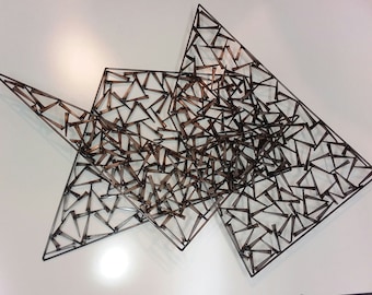 May include: Abstract wall art made of metal, featuring a geometric design of overlapping triangles. The triangles are formed by a network of smaller, interconnected metal pieces.