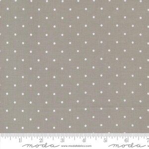 May include: A fabric swatch featuring a repeating pattern of white polka dots on a muted gray background. The fabric has a textured appearance and is suitable for various sewing and crafting projects. The image includes a ruler along the bottom edge.