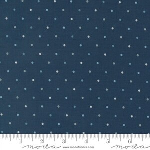 May include: Dark blue fabric with a repeating pattern of small, evenly spaced white and light blue polka dots. The fabric has a ruler along the bottom edge, with the word "moda" printed on the bottom left and right.