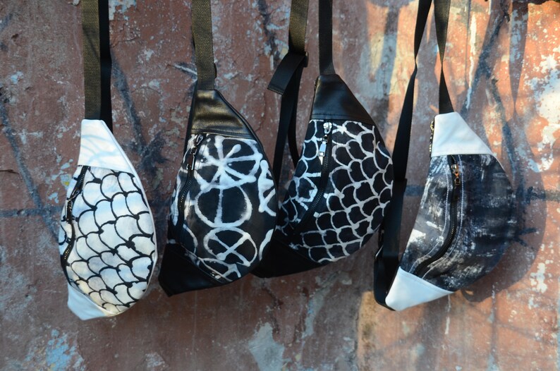 May include: Four black and white patterned fanny packs with adjustable straps. The fanny packs have different patterns, including a geometric pattern, a floral pattern, and a fish scale pattern.