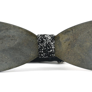 May include: A gray wooden bow tie with a black and white patterned band. The bow tie is tied and ready to wear.