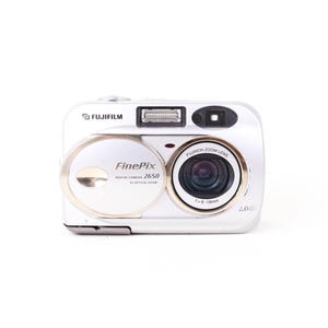 Op de afbeelding: Een zilverkleurige Fujifilm FinePix 2650 digitale camera met een Fujinon zoomlens met een brandpuntsafstand van f=6-18mm. De voorzijde toont de merknaam, het modelnummer, een 2,0 megapixel indicator en een ingebouwde flitser.