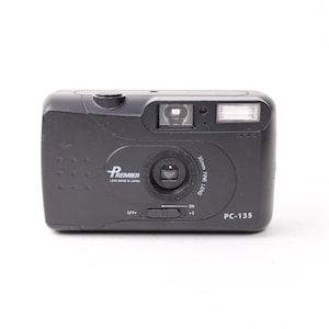 May include: A black Premier PC-135 35mm film camera featuring a 30mm fine lens, a built-in flash, and a sliding power switch on the front. The camera body displays the brand name Premier and the model number PC-135 in white text.