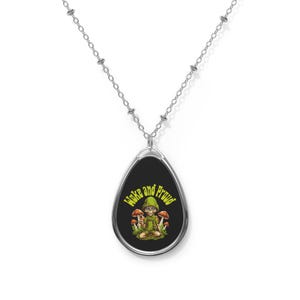 May include: Silver-toned necklace with an oval pendant featuring a cartoon figure in a green outfit, surrounded by mushrooms. The text "Woke and Proud" is in green. The pendant is suspended from a delicate chain.
