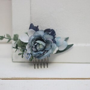 Pu&ograve; includere: Un pettine per capelli floreale blu e bianco con un pettine argentato. Il pettine &egrave; decorato con fiori blu e bianchi e verde.