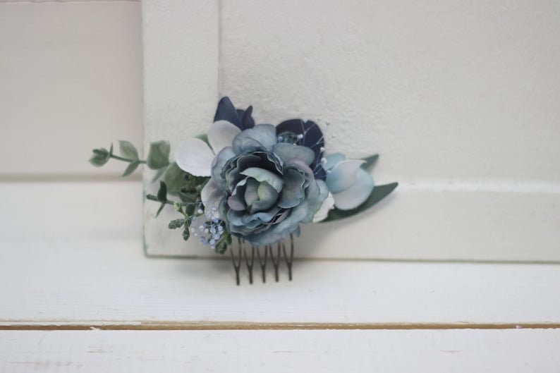 Pu&ograve; includere: Un pettine per capelli floreale blu e bianco con un pettine argentato. Il pettine &egrave; decorato con fiori blu e bianchi e verde.