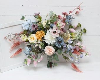 May include: A bouquet of artificial flowers in shades of pink, blue, and yellow. The bouquet includes roses, hydrangeas, and other flowers.