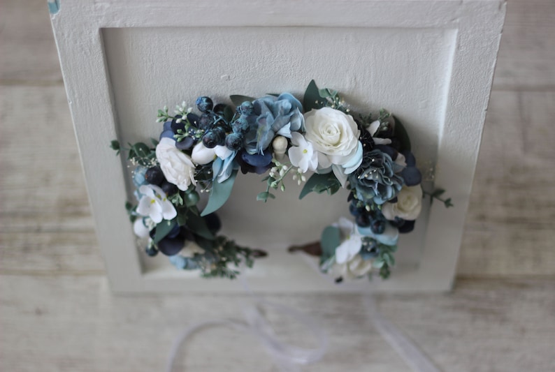 Pu&ograve; includere: Una corona floreale blu e bianca con fiori bianchi e foglie blu. La corona &egrave; realizzata con fiori di seta ed &egrave; perfetta per un matrimonio o un'altra occasione speciale.