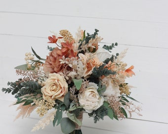 May include: A bouquet of faux flowers in shades of peach, cream, and green. The bouquet includes roses, hydrangeas, and other floral elements.