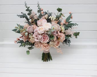 May include: A blush pink and green bridal bouquet with roses, eucalyptus, and other greenery.