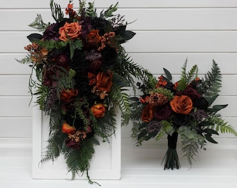 May include: A cascading bridal bouquet and a smaller round bouquet featuring deep burgundy, burnt orange, and black artificial roses mixed with green ferns, eucalyptus leaves, and small berry clusters, arranged with dark stems and foliage.