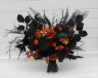 May include: A bouquet featuring orange and black roses, berries, and foliage. The arrangement includes black leaves, fern fronds, and branches, creating a striking contrast. The stems are bound with green tape, and the background is a white surface.