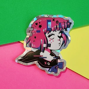 May include: Holographic sticker depicting an anime-style character with pink hair and a glitch effect. The character wears a black uniform with a blue bow and the text "xo". The sticker has a silver border and is set against a colourful background.