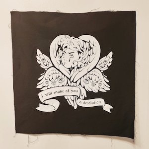 May include: Black square fabric with a white illustration of an angel with multiple eyes and wings. The text "I will make of you a desolation" is on a banner below the angel.