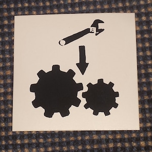 May include: Black and white illustration of a wrench above two gears. The wrench is pointing down at the gears.