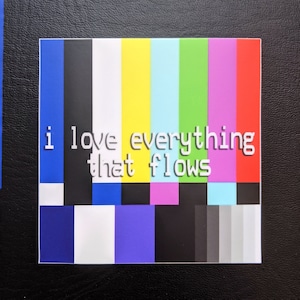 May include: A square sticker with a colourful vertical bar design, featuring the text "i love everything that flows" in white. The background is black.