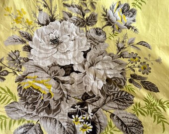 May include: A yellow fabric with a floral pattern featuring grey and white roses, green leaves, and yellow accents.