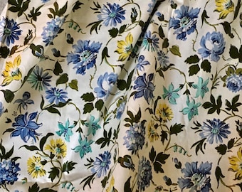 May include: White fabric with a floral pattern featuring blue, yellow, and green flowers. The fabric has a vintage feel.