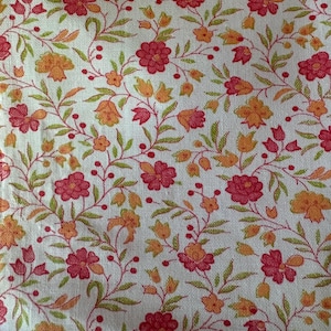 以下が含まれることがあります： 白地を背景に、赤とオレンジの花、緑の葉、小さな赤い実が繰り返される模様のフローラル生地。生地は、リネンやコットンを思わせる、テクスチャード加工が施されています。