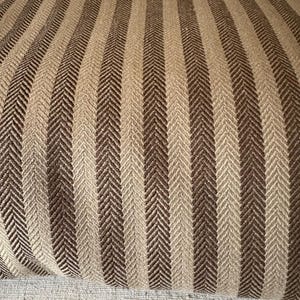 K&ouml;nnte beinhalten: Nahaufnahme eines Stoffes mit vertikalem Streifenmuster. Die Streifen wechseln sich in Hellbeige und Dunkelbraun ab. Der Stoff hat ein Fischgr&auml;tgewebe, das Textur verleiht. Geeignet f&uuml;r Polster oder Heimdekoration.
