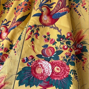 May include: Yellow fabric with a repeating pattern of red and blue birds perched on branches with flowers and fruit. The fabric has vertical stripes and a vintage aesthetic.