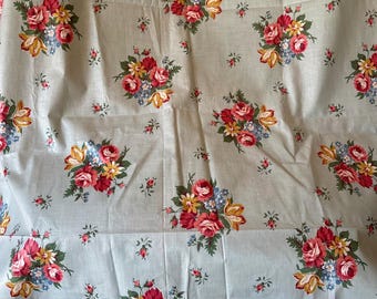 May include: A light blue fabric with a repeating floral pattern. Clusters of red, yellow, and blue flowers are scattered across the fabric. The flowers are detailed with green leaves and stems. The fabric appears to be a cotton or linen material.