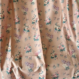 May include: Pink fabric with a floral pattern featuring pink, white, and purple flowers. The fabric has a subtle sheen and a soft texture.