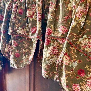 Pu&ograve; includere: Un set di quattro tendine floreali marroni con un bordo a festoni e un bordo marrone e dorato. Le tendine presentano un motivo floreale con fiori rosa, bianchi e gialli.