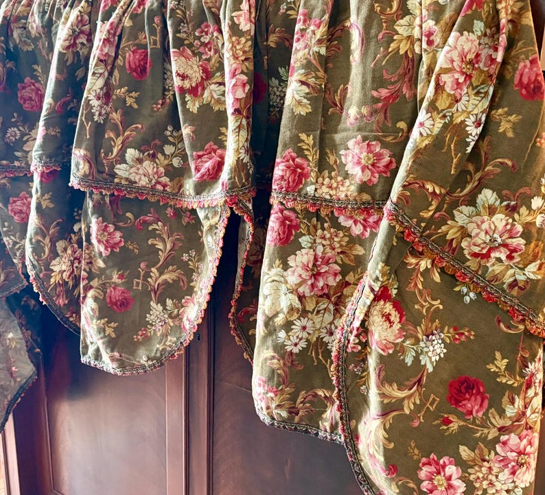 Pu&ograve; includere: Un set di quattro tendine floreali marroni con un bordo a festoni e un bordo marrone e dorato. Le tendine presentano un motivo floreale con fiori rosa, bianchi e gialli.