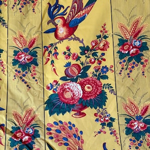May include: Yellow fabric with a repeating pattern of red and blue birds, flowers, and foliage. The design includes vertical stripes and a variety of floral arrangements. The fabric has a vintage, decorative style.