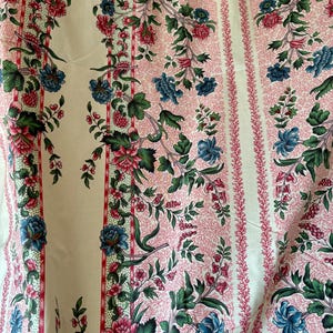 Könnte beinhalten: Ein Stoff mit einem sich wiederholenden Muster aus vertikalen Streifen und Blumenmotiven. Das Design umfasst korallenartige rosa Texturen, grüne Blätter sowie rote, rosa und blaue Blüten auf einem cremefarbenen Hintergrund.