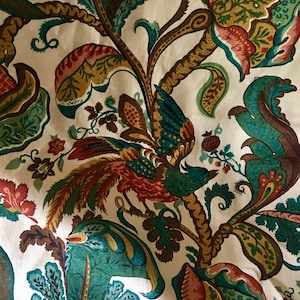May include: A white fabric with a teal, brown, and red floral pattern. The pattern features a bird with a long tail and a leafy branch.