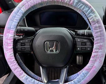Funda universal para volante con diseño de retazos en tonos pastel y agarres antideslizantes.