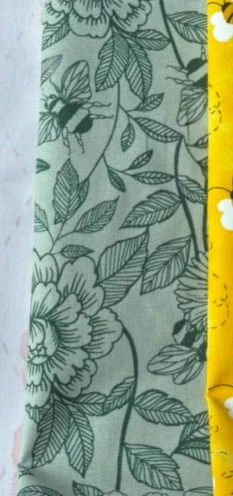 Puede incluir: Tela floral verde con un patr&oacute;n repetido de flores, hojas y abejas. La tela tiene un fondo verde claro y dise&ntilde;os florales verde oscuro.