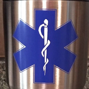 May include: A stainless steel tumbler with a blue star of life and a white caduceus symbol.