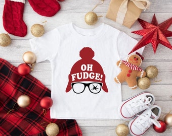 May include: White baby onesie with a red Christmas hat graphic and the text "Oh Fudge!" printed on it. The onesie is surrounded by Christmas decorations, including ornaments, a gingerbread man, and a red star.