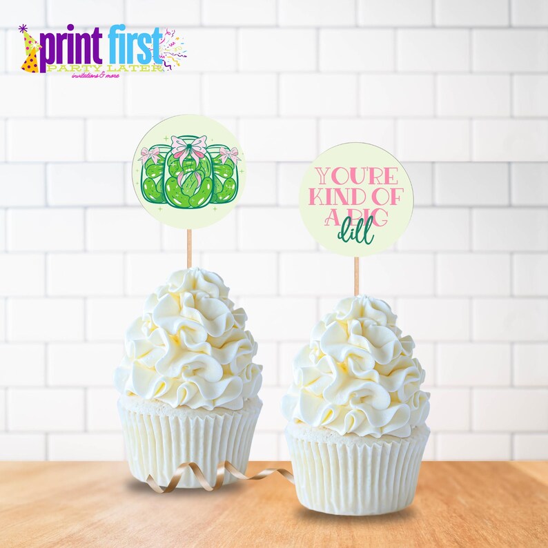 Puede incluir: Dos cupcakes con glaseado blanco y un adorno de cupcake con tem&aacute;tica de pepinillos verdes que dice "You're kind of a big dill" y un adorno de cupcake con un dibujo de tres frascos de pepinillos.